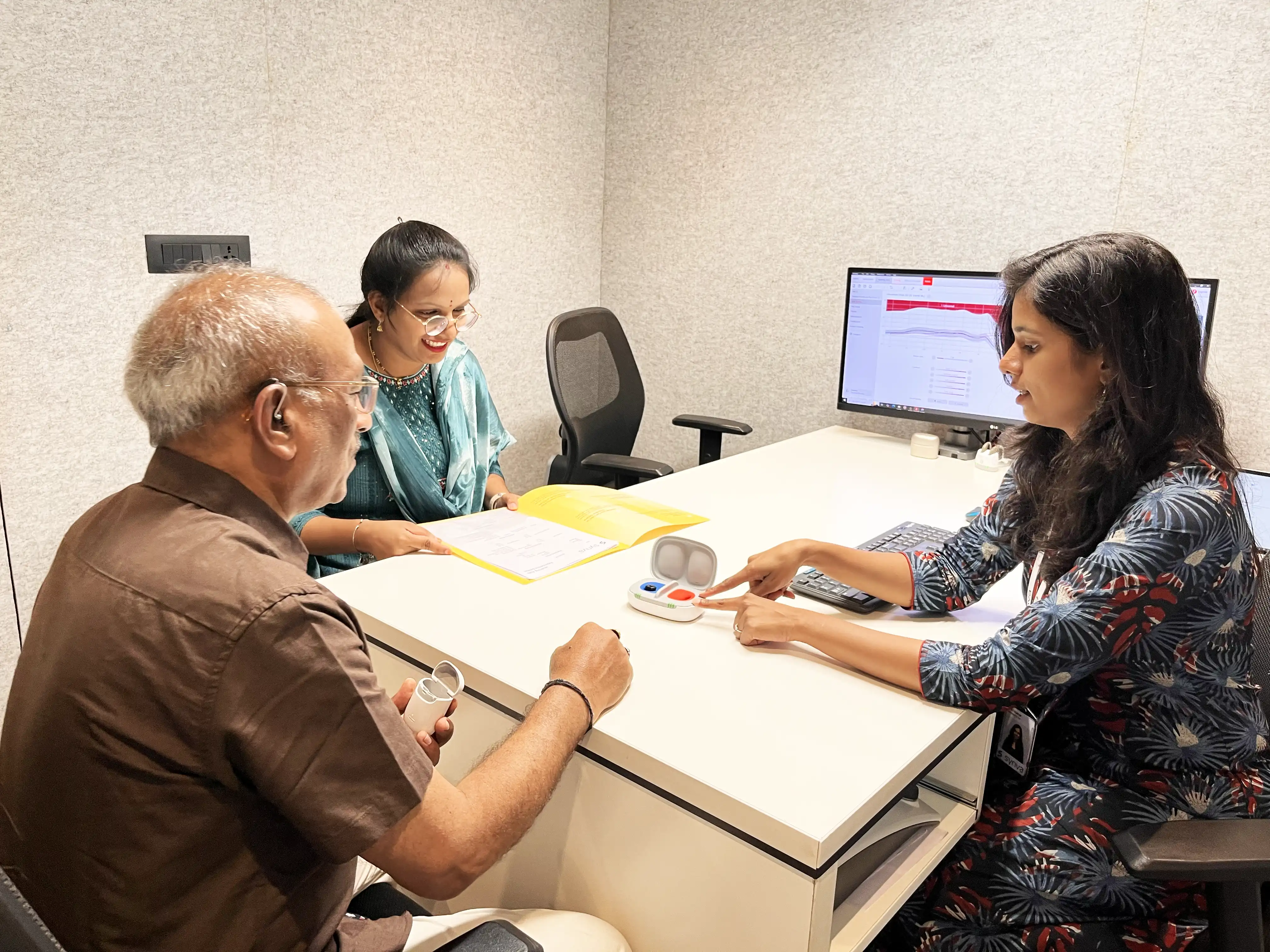 A patient and his family trying hearing aids with a Synva audiologist at the consultation desk